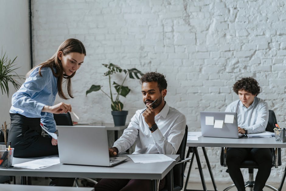 A group of professionals collaborating in a modern office setting, engaging with technology and teamwork