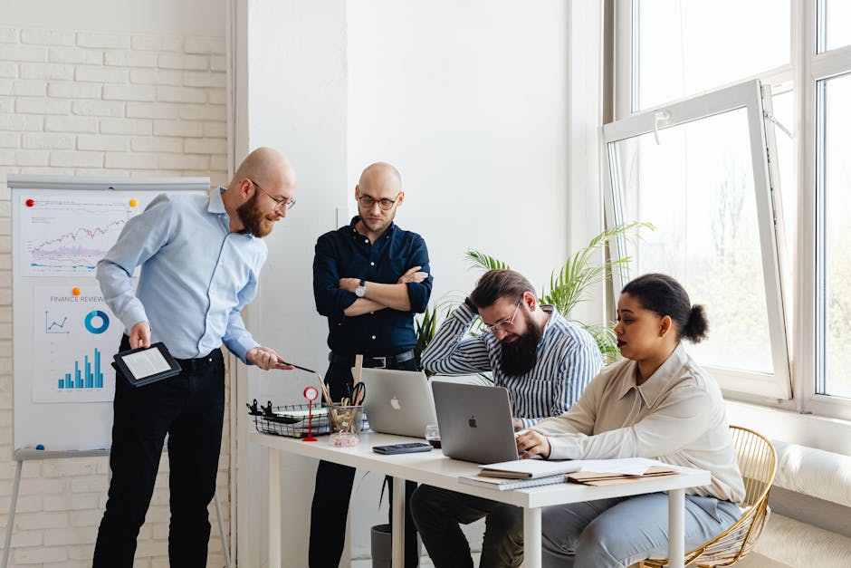 A diverse team discusses strategy in a modern office setting with laptops and charts