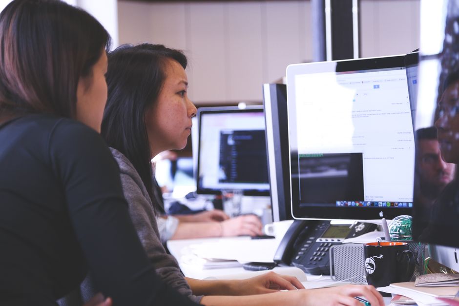 Two women working together on code at a computer.